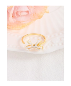 Detail of a bow-shaped ring with white pearls and small crystal on a ceramic tray