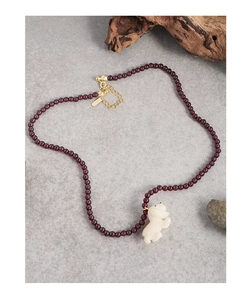 Close-up of S925 silver necklace with red garnet beads and white carved puppy pendant