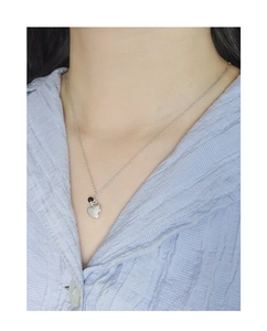 Detail of silver S925 heart pendant and black bead necklace on a blue pleated shirt