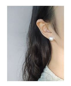 Close-up of minimalist brushed silver ball earrings worn by a model for a stylish look