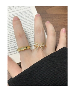 Close-up of golden bow ring with white pearls and sparkling crystal on model's finger