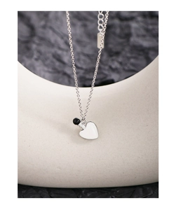 Detail of S925 sterling silver necklace with heart enamel pendant on stone texture
