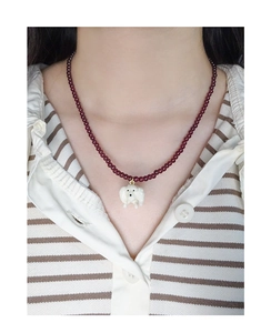 Detail of beaded garnet necklace with a white 3D puppy pendant on an Asian model