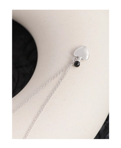 Close-up of S925 silver heart necklace with black agate bead on ceramic display