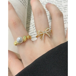 Elegant gold bow pearl ring set with sparkling details and a modern wavy band