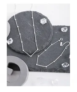 Detail of S925 sterling silver bamboo joint chain necklace on grey stone background