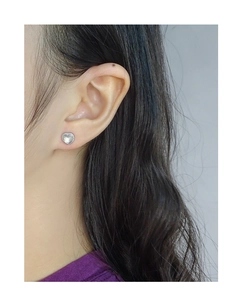 Close-up of heart-shaped silver earrings with moonstone on a female ear