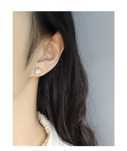 Close-up of heart agate stud earrings with beaded silver borders on woman's ear
