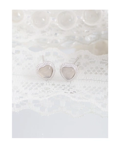 Macro shot of silver heart studs with opal stones on a white lace background
