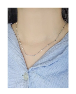 Detail of silver bamboo joint necklace worn over a light blue striped shirt