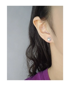 Close-up of heart-shaped S925 silver stud earring with white shell inlay on model