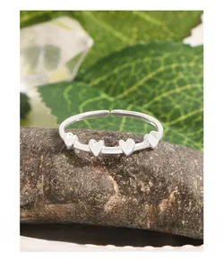 Detail view of S925 silver ring with four small hearts on natural brown rock background