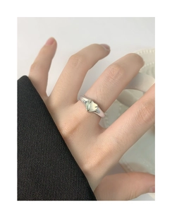 Gros plan d'une bague en argent S925 avec agate vert clair en forme de cœur sur la main