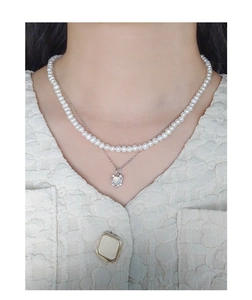 Close-up of a layered pearl and silver necklace with a textured heart pendant