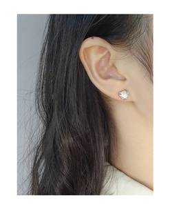 Close-up of heart-shaped earring with wrinkled silver texture and mother of pearl on ear