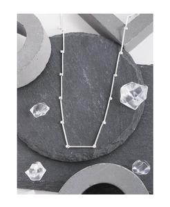 Close-up of a minimalist S925 silver bamboo-style necklace on grey stones