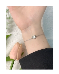 Gros plan détaillé du bracelet pendentif cœur en agate argent S925 au poignet avec fleurs