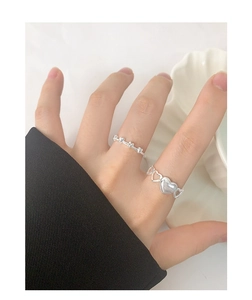 Detail of S925 sterling silver heart rings on a model hand with elegant white tray