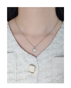 Close-up of S925 silver heart necklace with moonstone pendant on white tweed garment