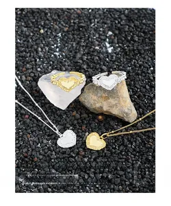 Detailed close-up of S925 sterling silver heart rings and necklaces on natural stone