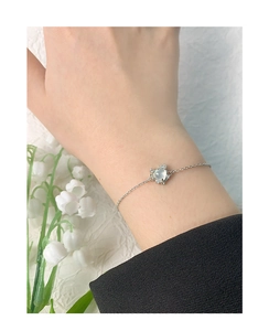 Gros plan du bracelet en argent S925 avec cœur en agate et détails de muguet