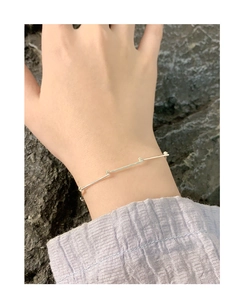 Détail du bracelet en argent massif S925 à maillons bambou porté au poignet sur tissu