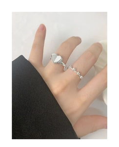 Stacked S925 sterling silver heart rings set worn against a black fabric sleeve