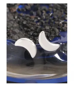 Macro shot of polished S925 sterling silver crescent moon stud earrings on blue glass