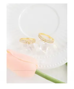 Détail de bagues nœud dorées avec zircons sur assiette blanche et tulipes
