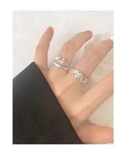 Detail of stacked S925 silver heart rings on hand with intertwined minimalist design
