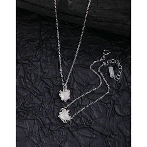 Parure en argent S925 avec pierres blanches en forme de cœur sur un fond noir texturé