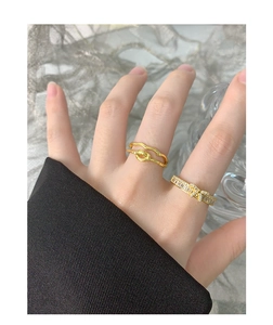 Détail d'une bague dorée à double nœud et d'une bague nœud avec zircons sur les doigts