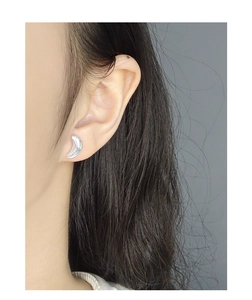 Close-up of polished silver crescent moon stud earrings worn on a female ear