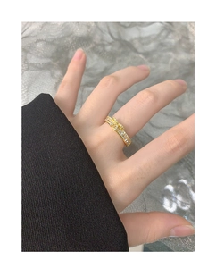 Détail d'une bague nœud dorée avec zircons sur main avec dentelle et tissu