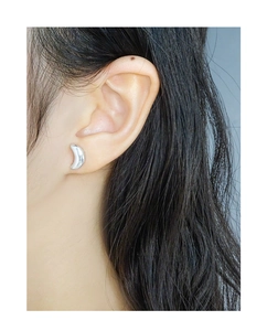 Close-up of minimalist silver moon earrings worn by a model in a side profile view