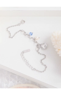 Close-up of S925 silver bracelet featuring natural pearl and blue bead on white coral
