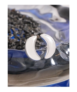 Detailed view of silver crescent moon stud earrings with white enamel finish on dark stones