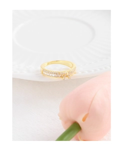 Détail d'une bague nœud dorée avec zircons posée sur une assiette en céramique
