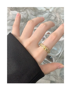 Détail d'une bague nœud dorée ornée de zircons carrés et ronds sur un doigt