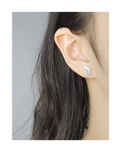 Close-up of crescent moon stud earring in polished silver finish on a female model's ear