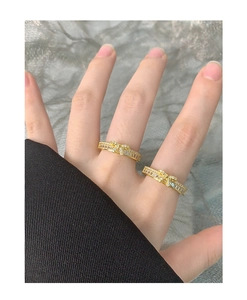 Gros plan d'une bague nœud dorée sertie de zircons portée sur les doigts