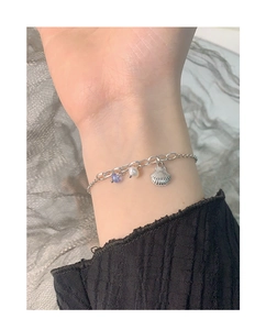 Detail of S925 silver bracelet featuring a shell charm, natural pearl, and purple bead