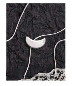 Detailed view of polished moon pendant on sleek silver snake chain necklace