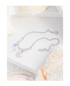 Detail view of S925 silver bracelet featuring shell charm, pearl and blue bead on coral