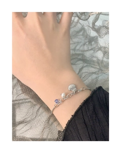 Detail of S925 silver bracelet featuring shell charm, pearl and purple crystal on wrist