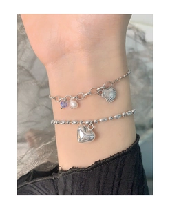 Detailed view of layered S925 silver bracelets with pearl, shell, and heart charms