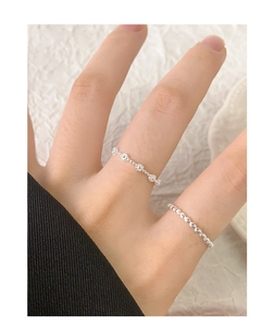 Primo piano di anello con fiori in argento S925 e fascia con perline indossati a mano