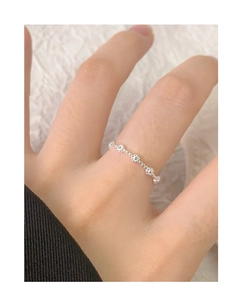 Dettaglio di un delicato anello a fiore in argento sul dito di una modella dal design pulito