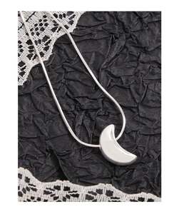 Detailed view of polished silver crescent moon pendant on a fine snake chain necklace