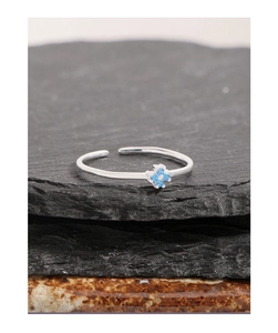 Macro d'une bague fleur en argent 925 avec zircons bleus sur un fond de pierre